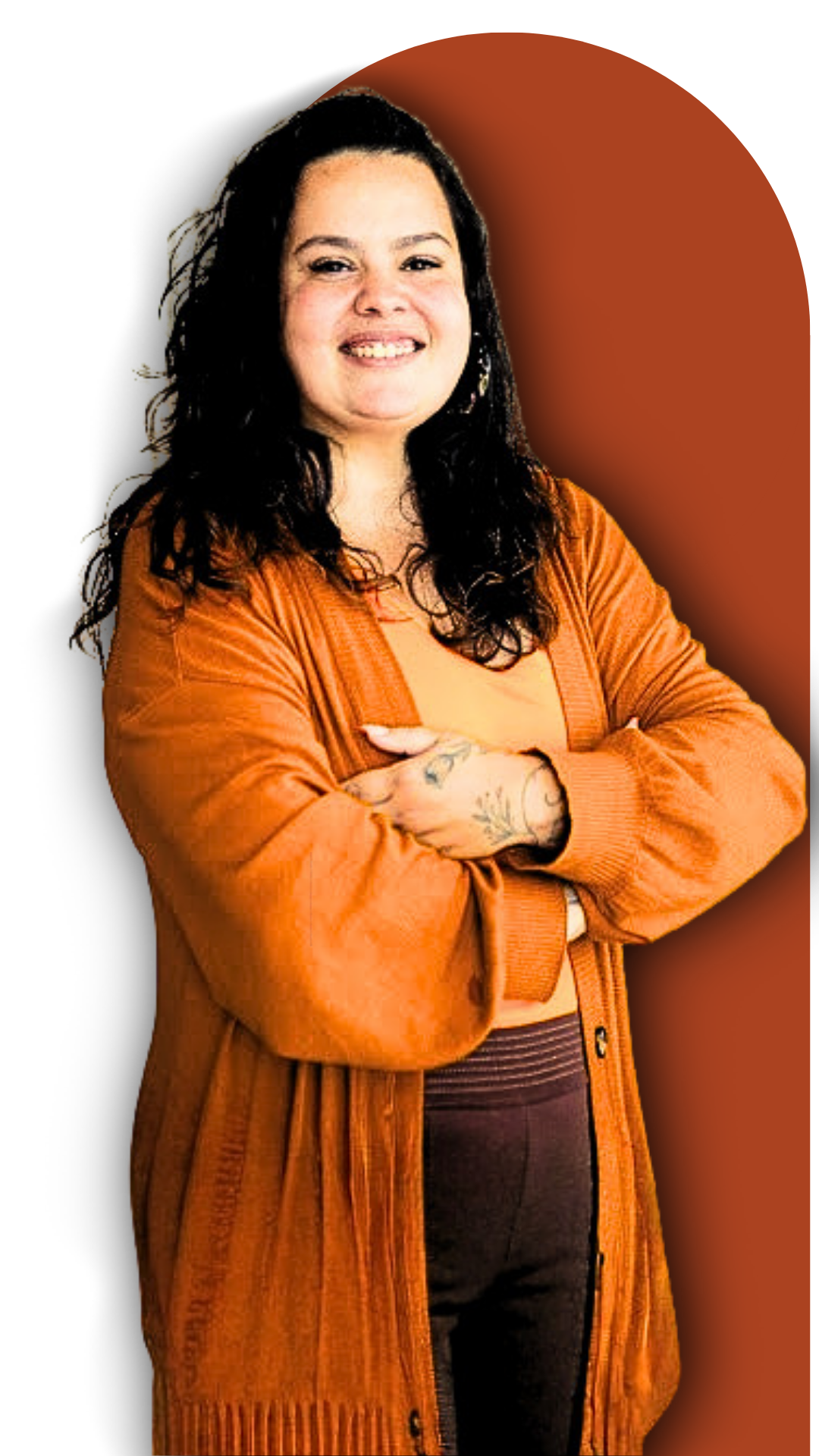 Fernanda Coelho, sorrindo, de cardigã laranja, braços cruzados